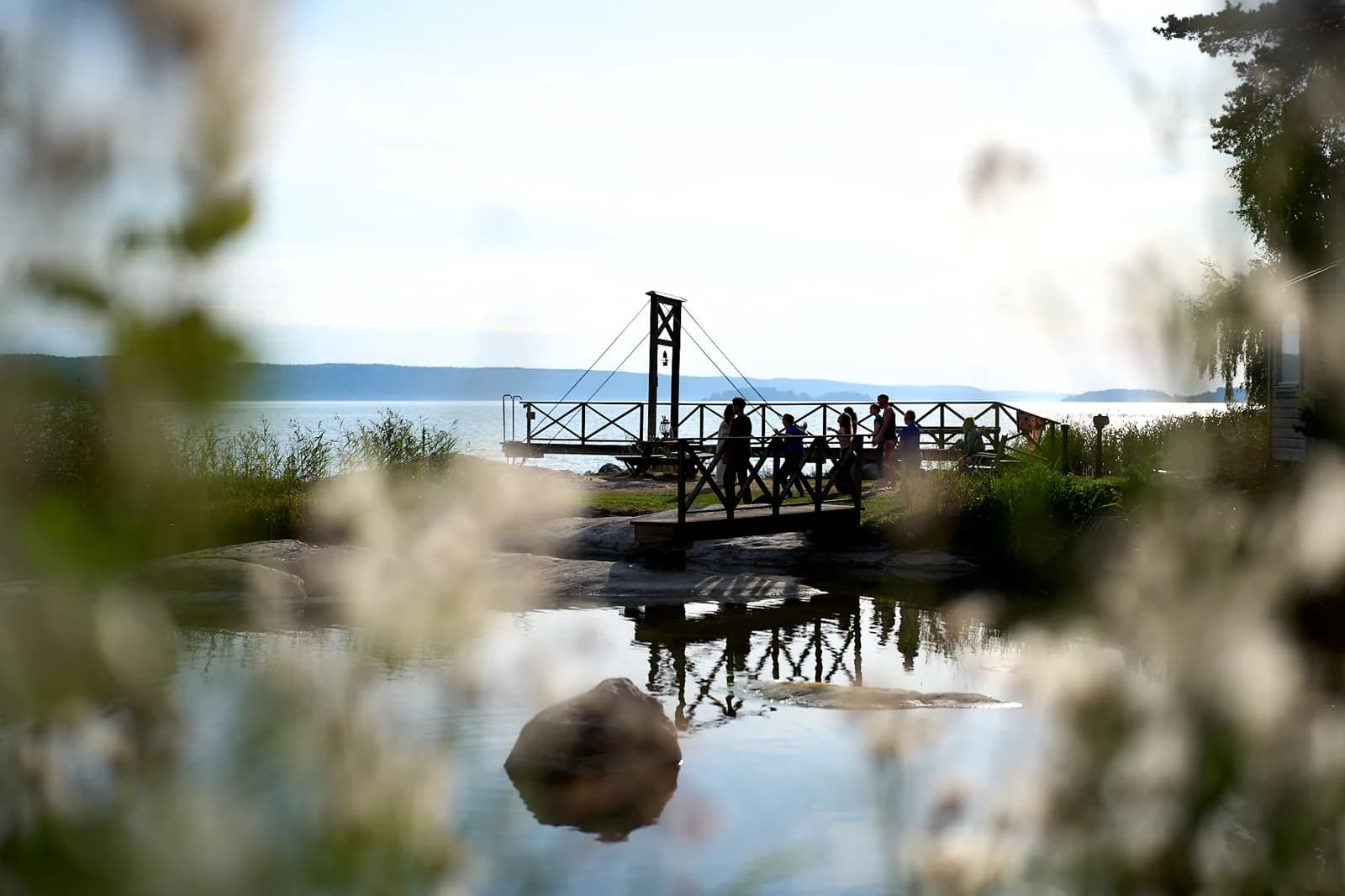 The wooden jetty and bell tower seen through leaves across the water.
