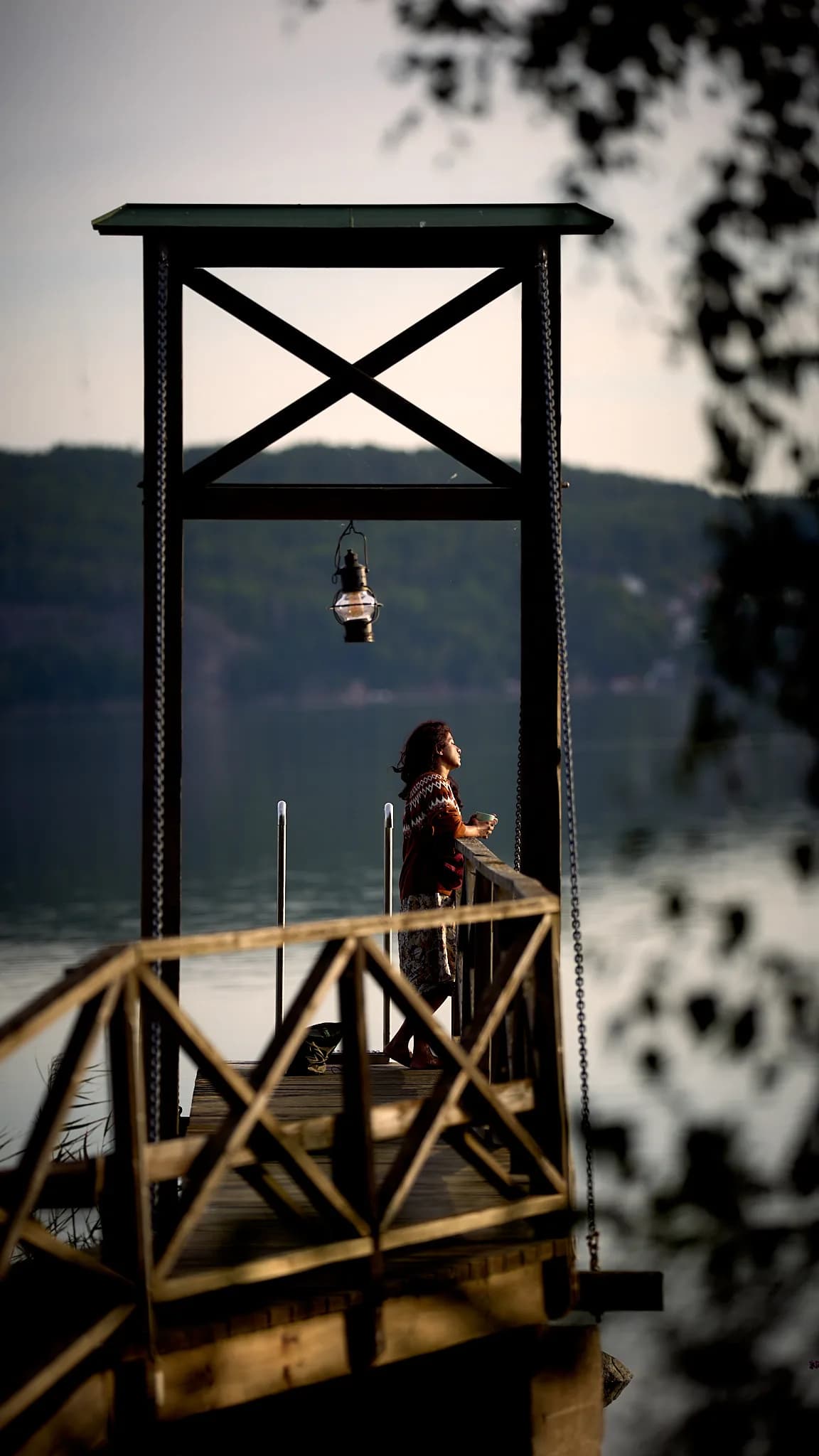 A person stands beneath the bell on the wooden jetty.