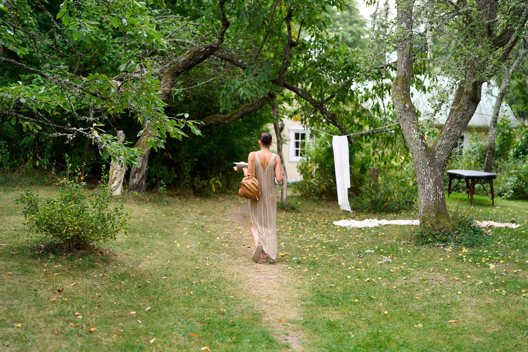 A participant walking between trees toward the house.