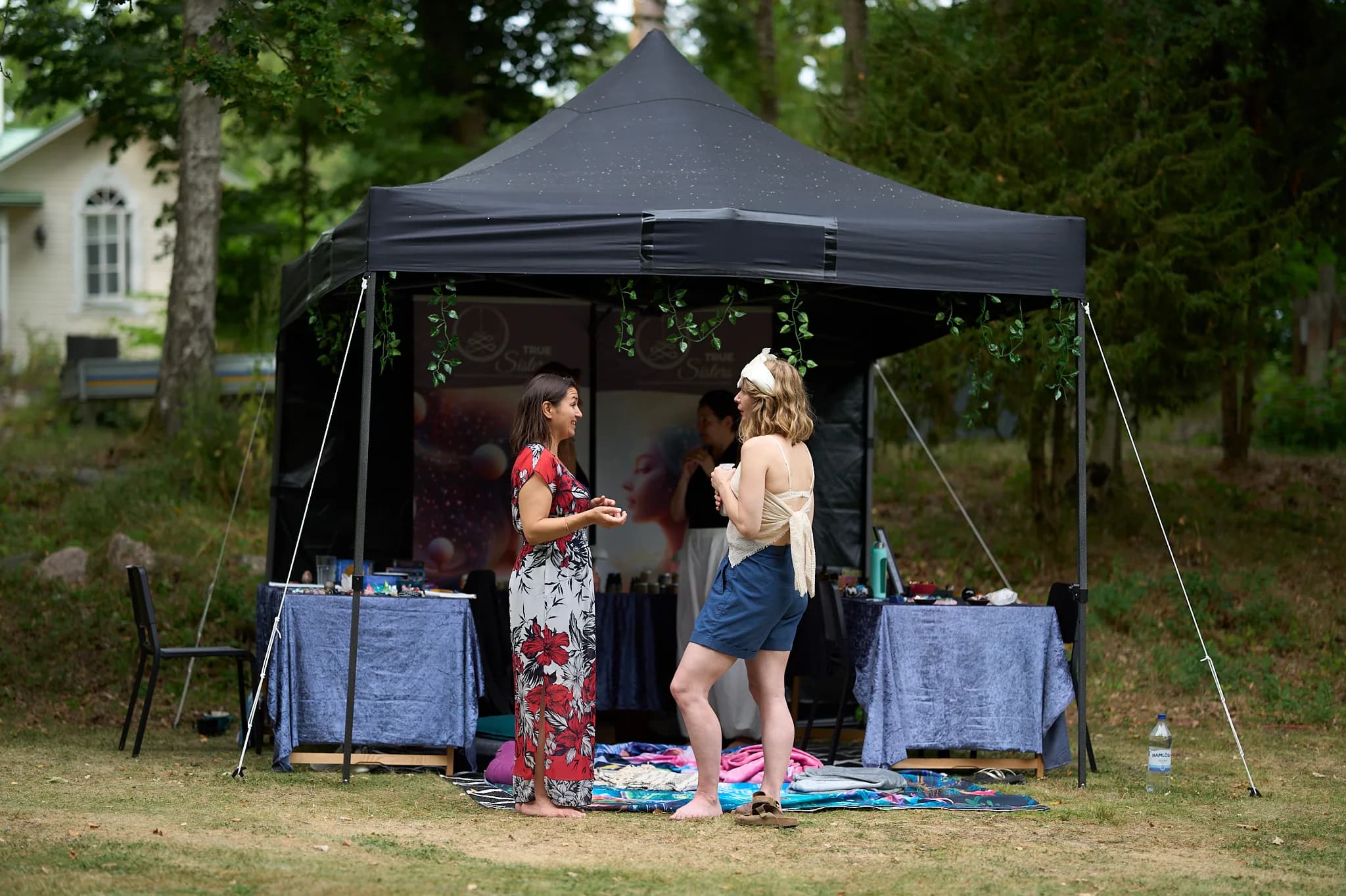 Two participants talking beside a small covered stall in the garden.