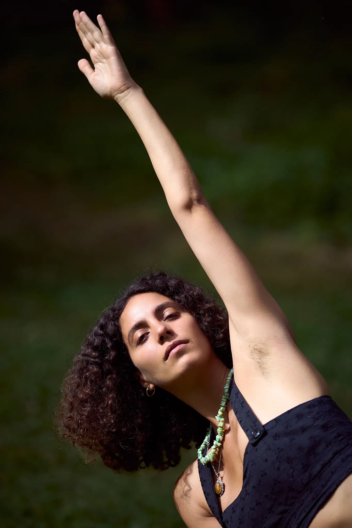 A participant stretching one arm overhead against a green woodland background.