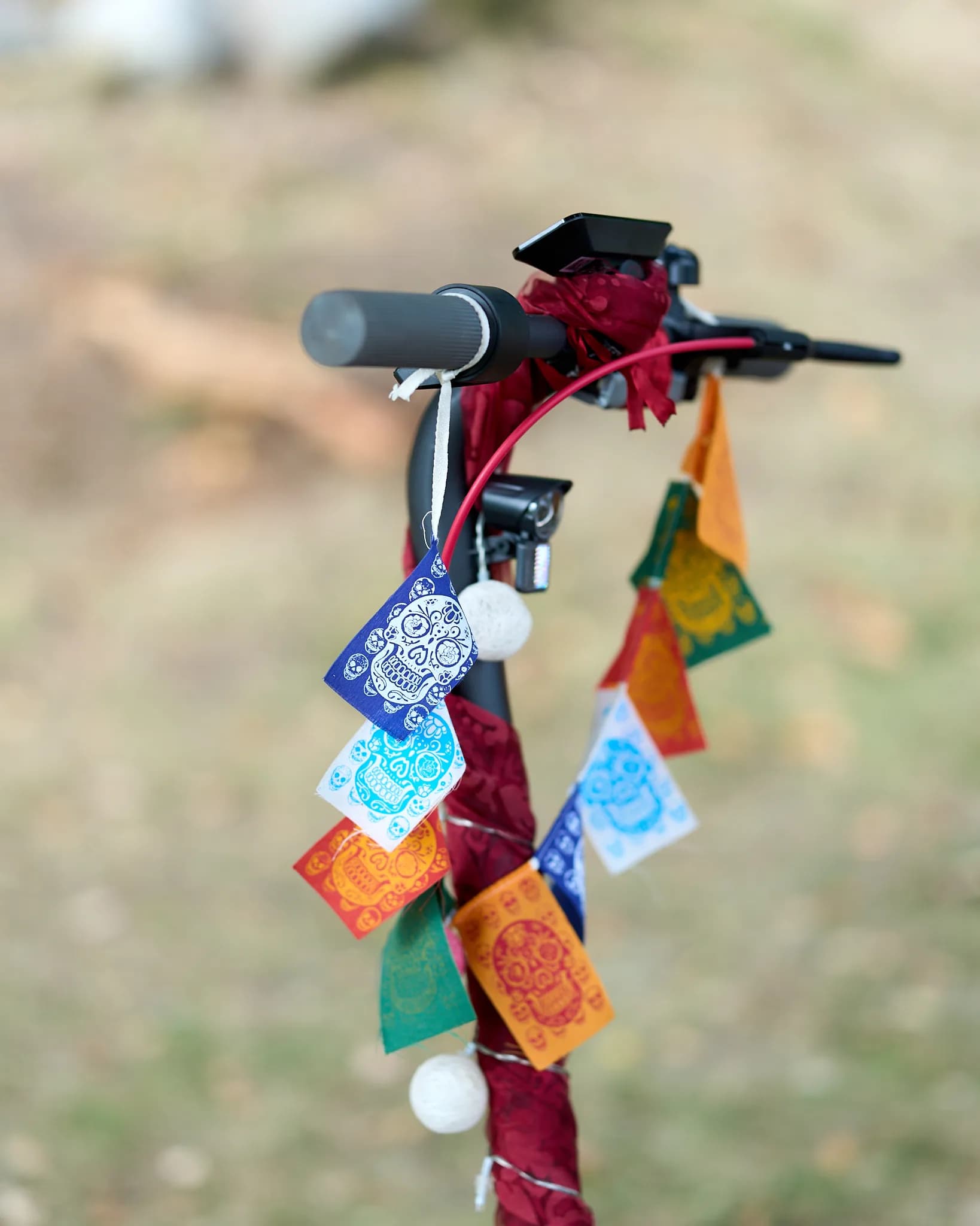 Colourful fabric flags tied around the handlebar of a scooter.