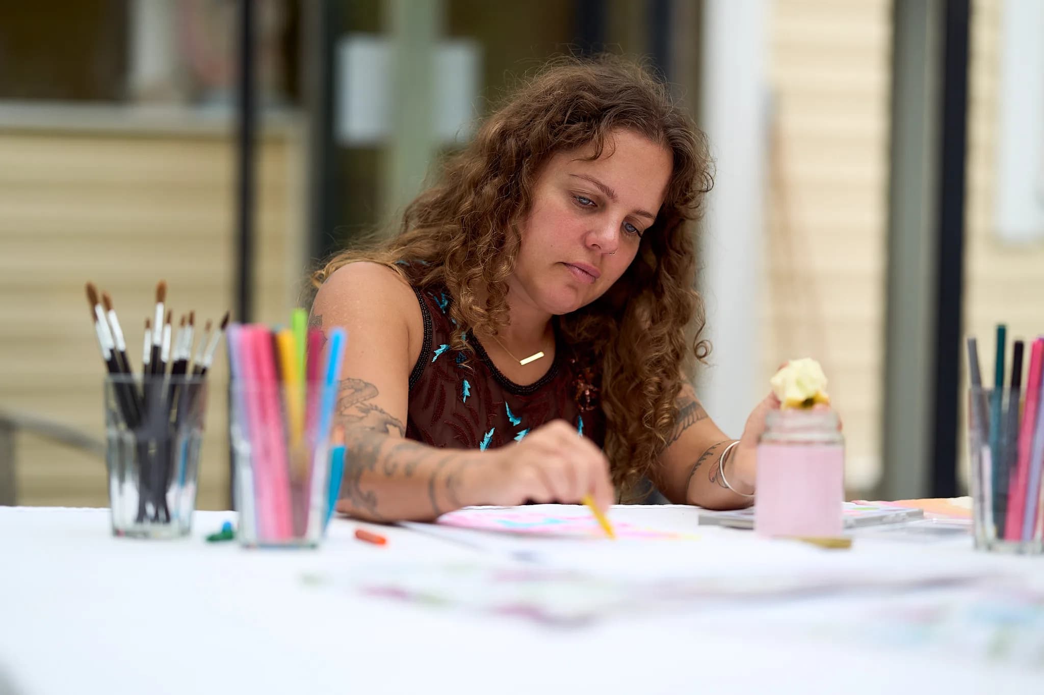 A participant drawing at a table with brushes and coloured pencils.