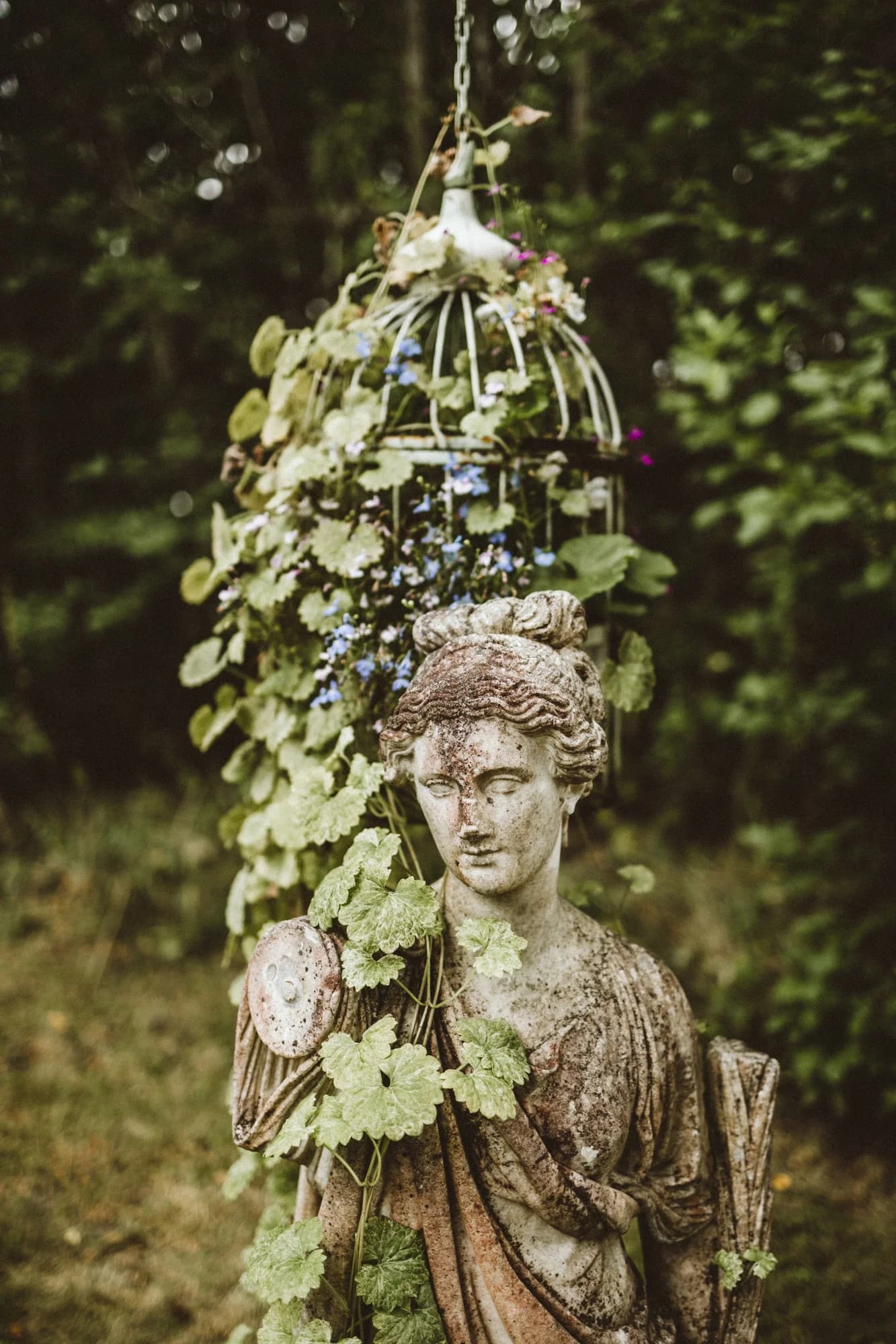 A weathered stone sculpture wreathed in climbing plants