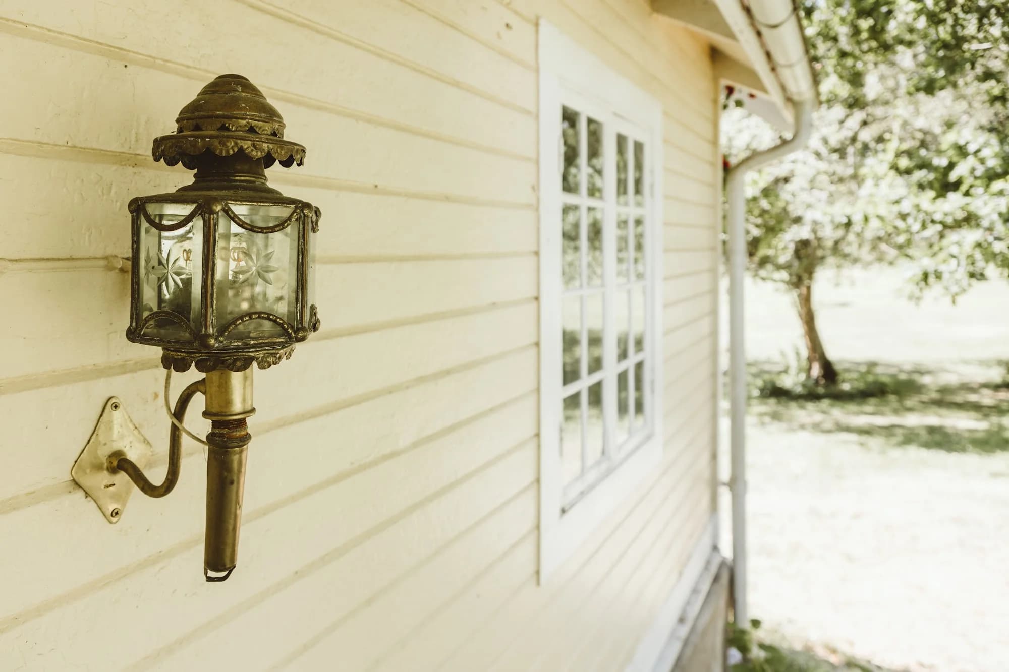 An antique brass lantern on the wall of the Gardener’s House