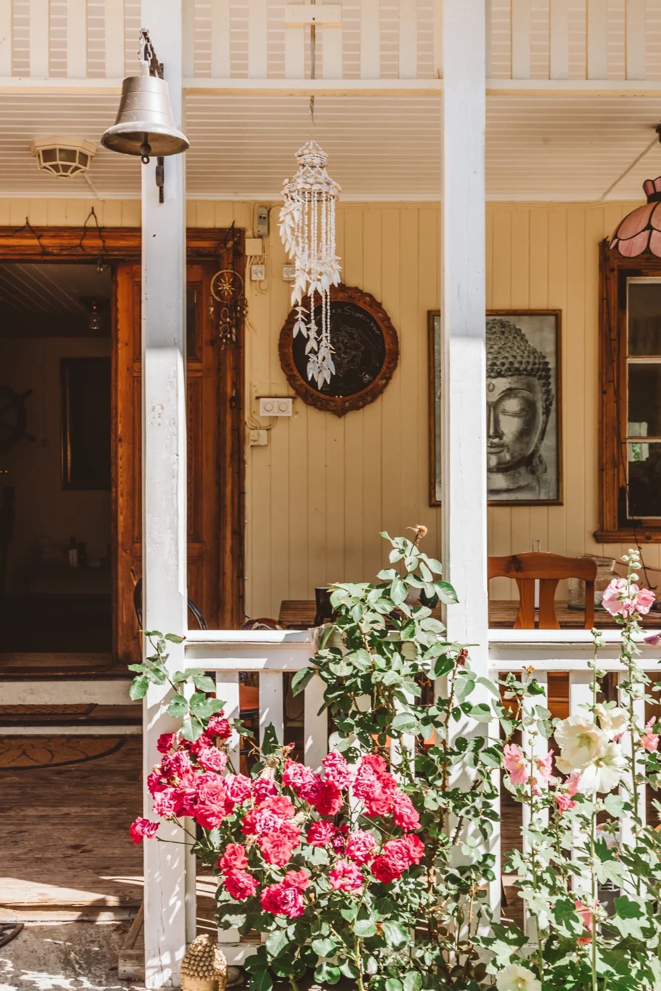 The Main House veranda with a brass bell, wind chimes and red roses