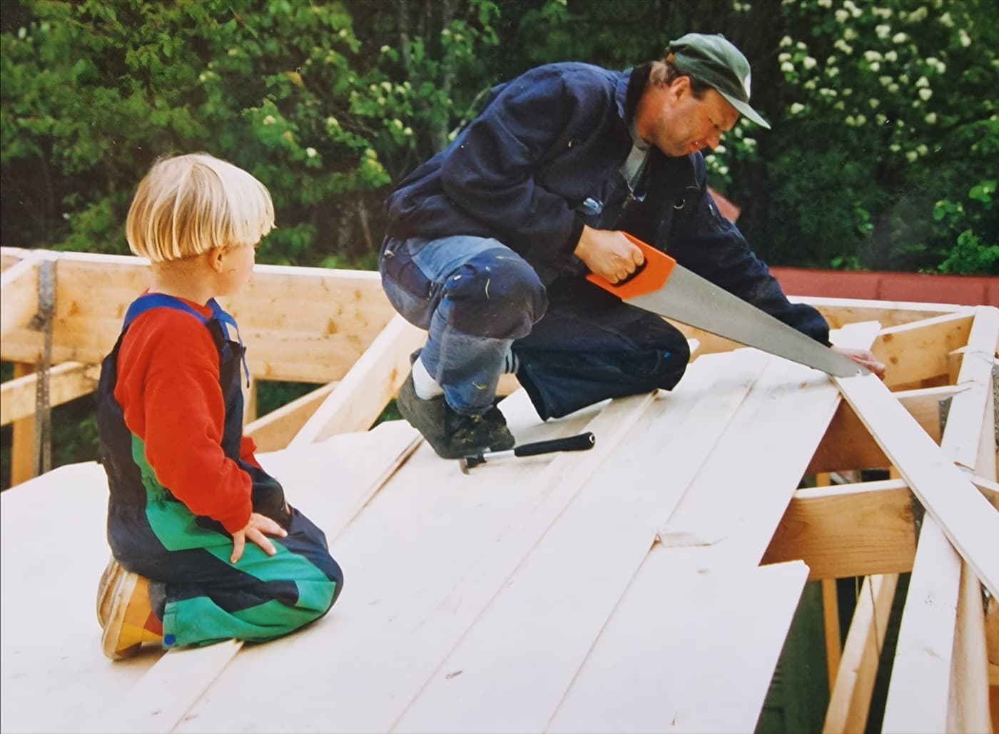 A child watching a man saw roof boards during the rebuilding