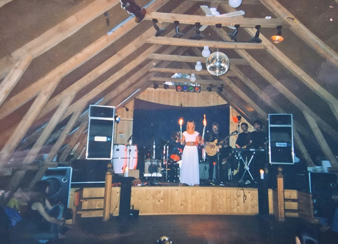 A concert on the wooden stage in the barn, under the roof beams and a disco ball