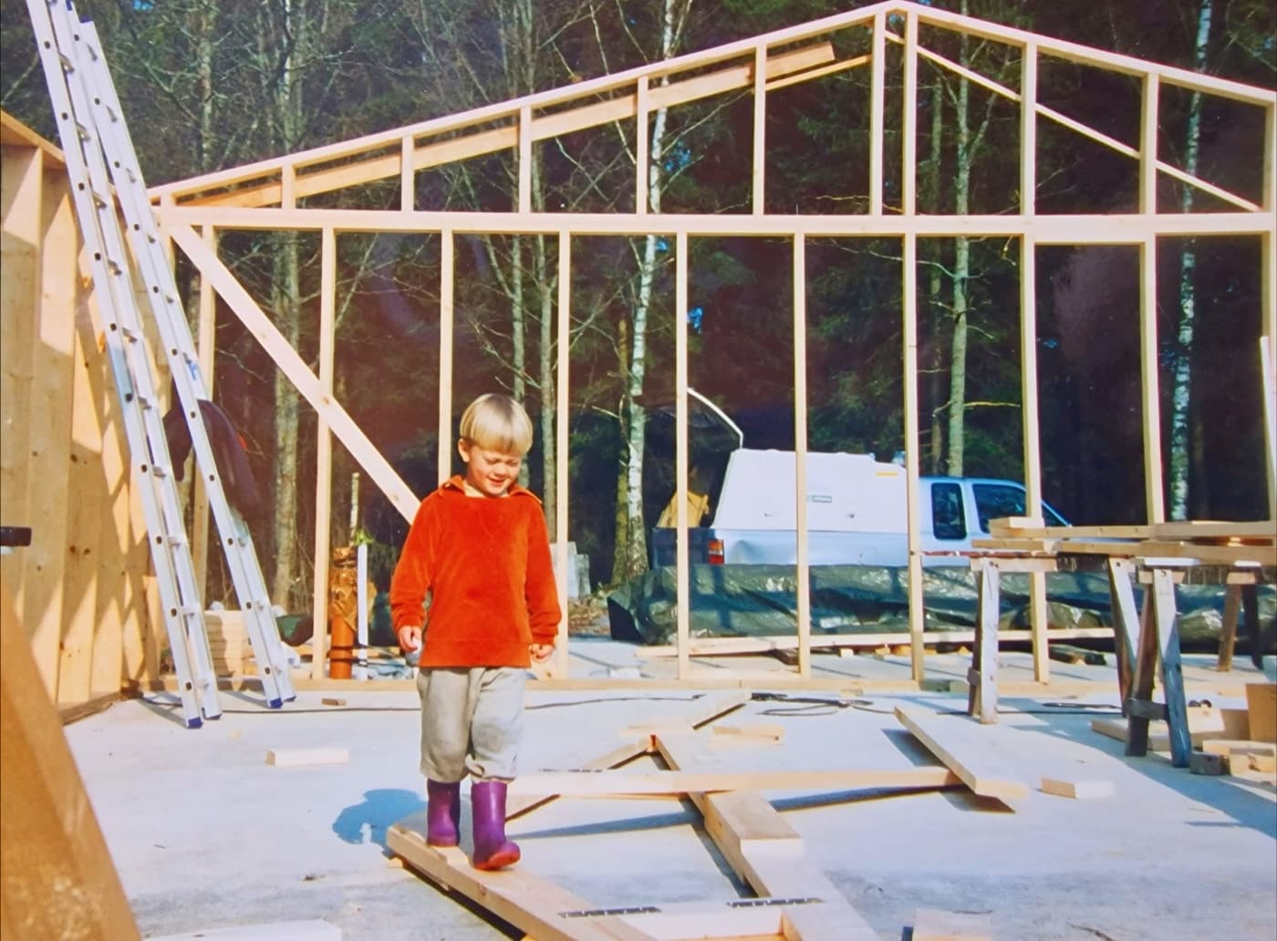 A child balancing on planks inside a newly raised timber frame