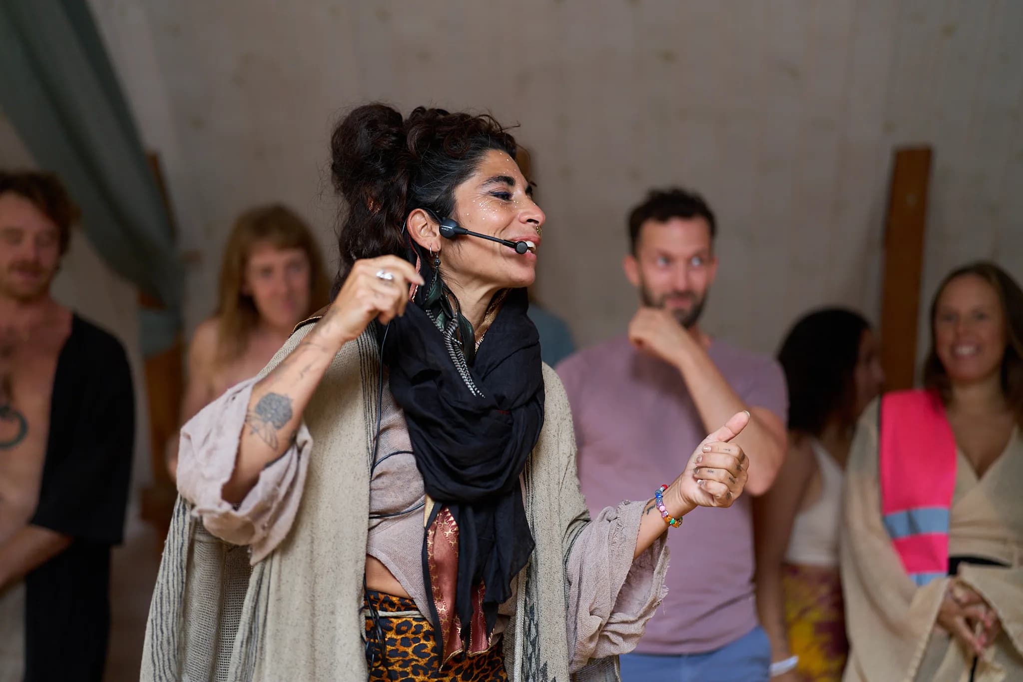 A smiling dancer with a headset microphone, with other participants facing the camera during Ecstatic Fusion.