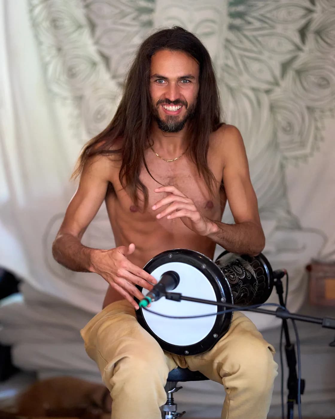 A seated musician holding a hand drum in the hall