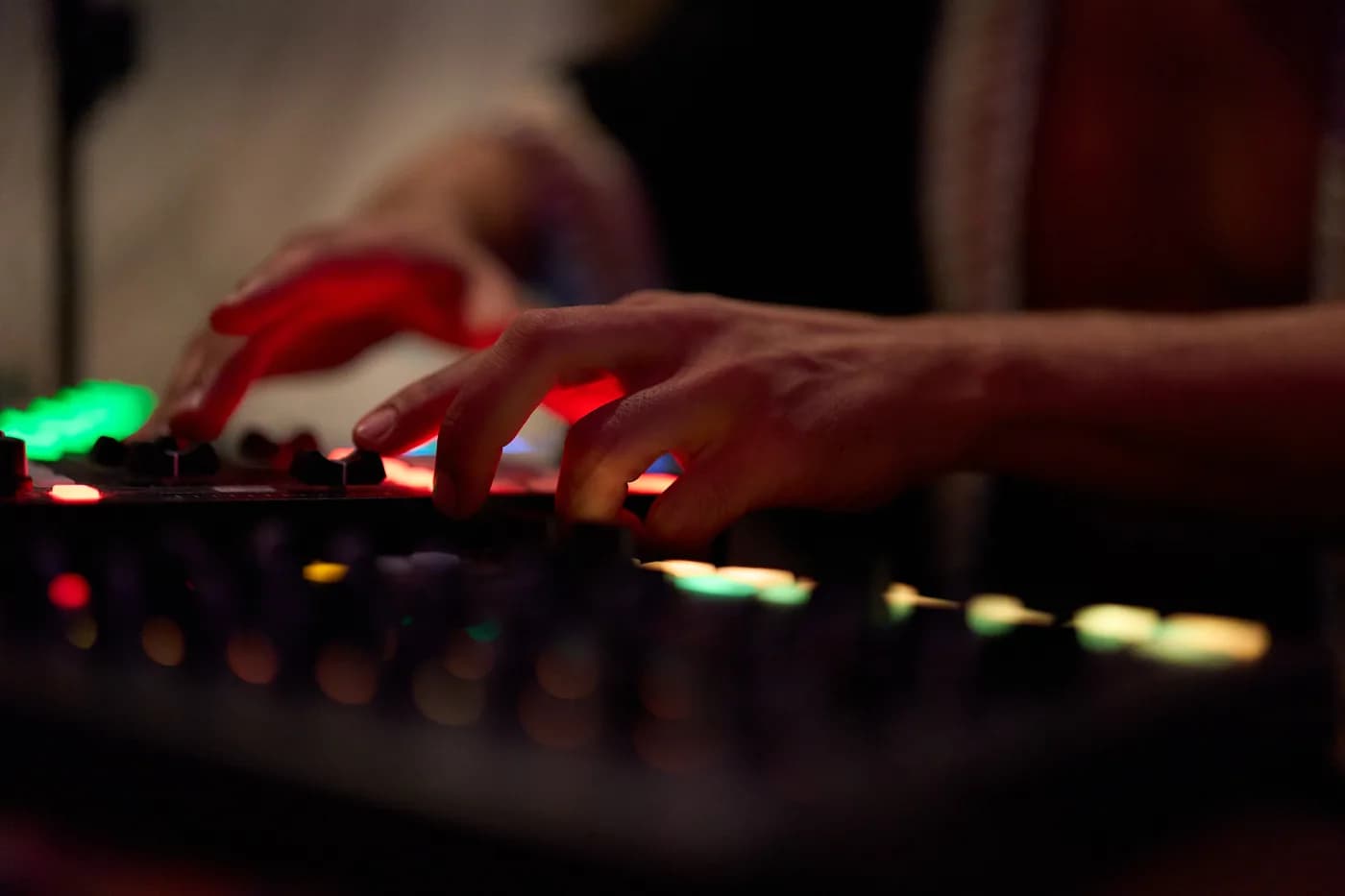 Hands adjusting illuminated controls on music equipment