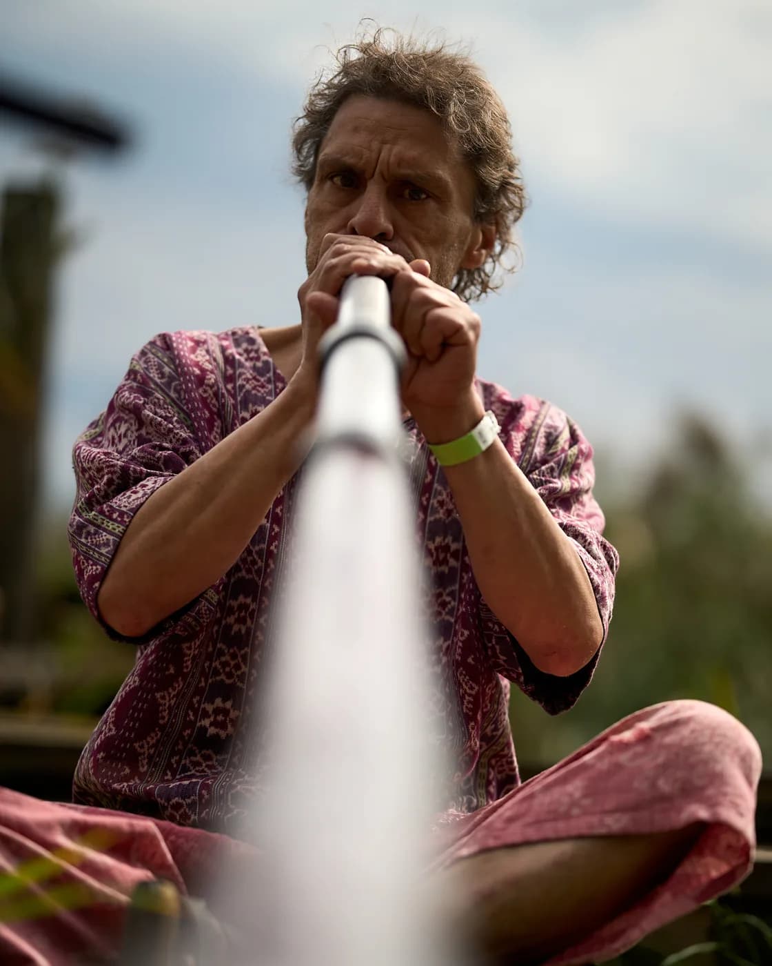 A musician playing a long wind instrument outdoors