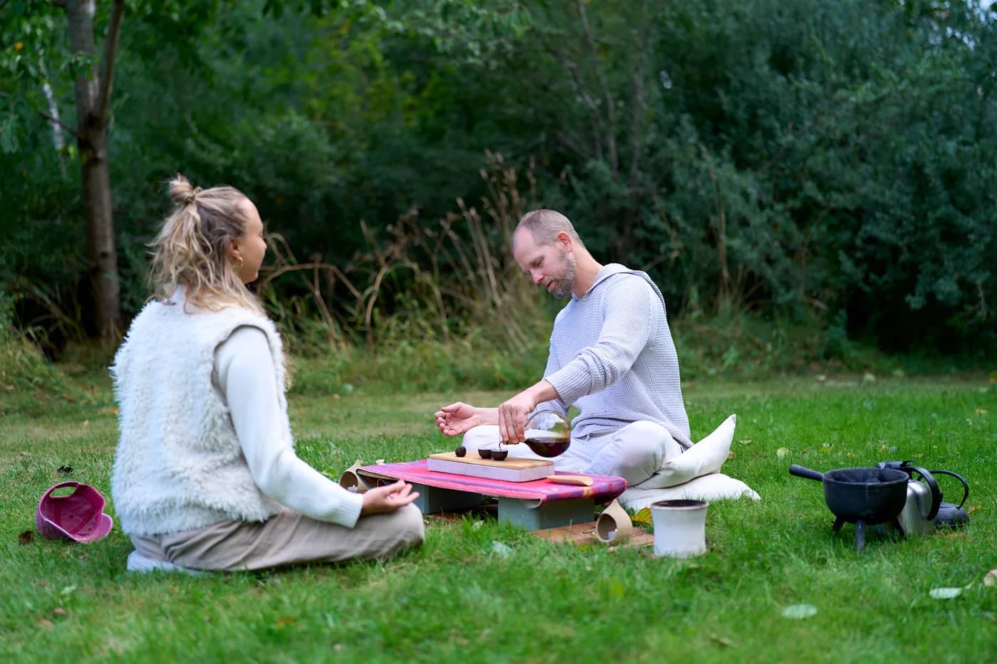 Two people sharing tea at a low table in the garden