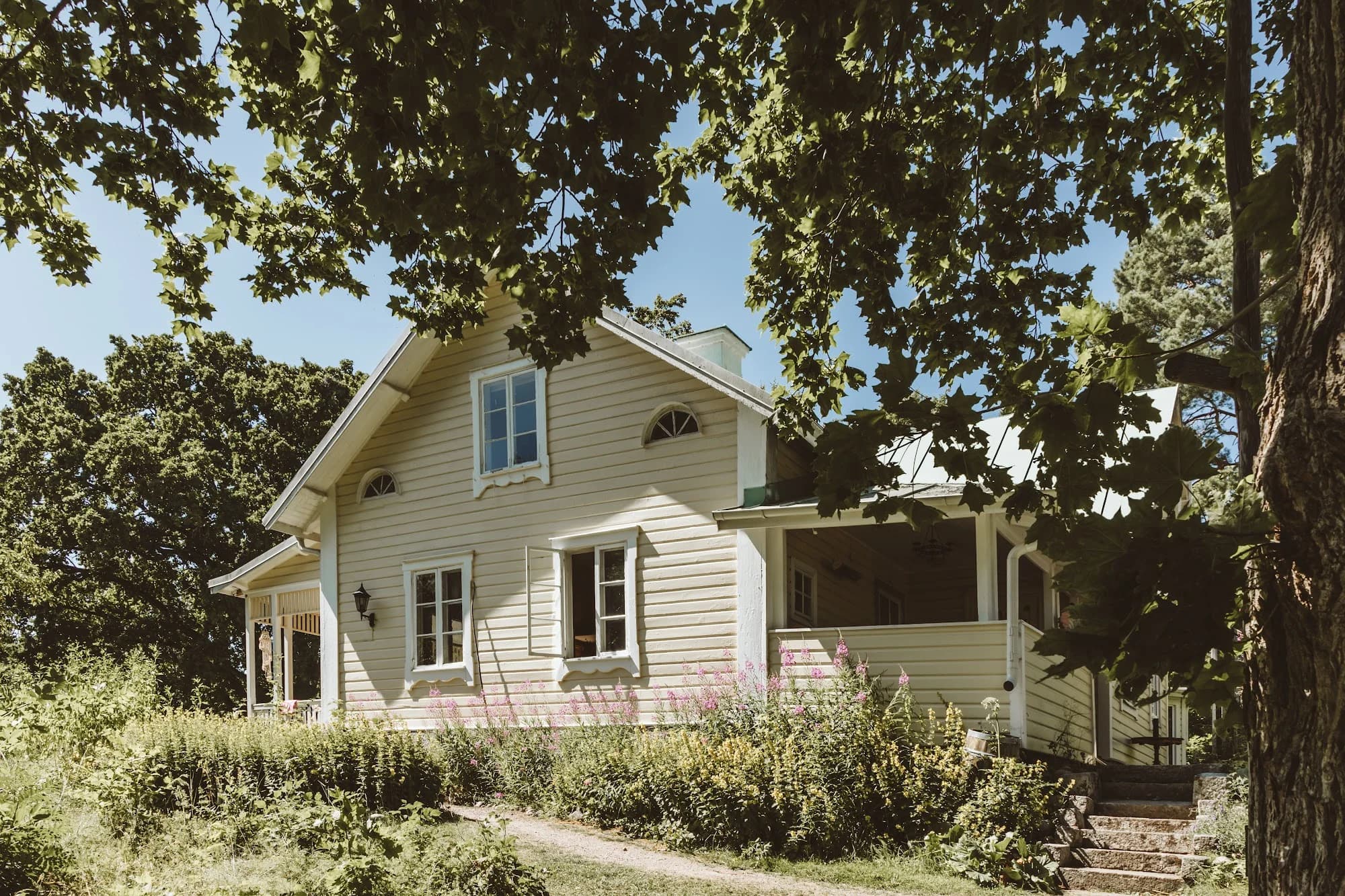 The pale yellow Main House at Skeppsudden seen through the trees